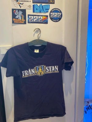 Sofialäktaren/Djurgården - Snygg mörkblå t-shirt med Djurgården sofialäktaren-tryck och sköldmotiv på bröstet. Klassisk rund hals och korta ärmar. Perfekt för dig som vill sticka ut med en unik och stilren tee.