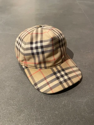 Burberry keps - Hej!! Jag säljer denna riktigt feta burberry keps. Den har den klassiska burberry mönstringen o passar perfekt till verkligen vad som helst, är bra för att setts lite lyx på vardagen. Ställ frågor om det är nått som undras, priset är inte hugget i sten!!
