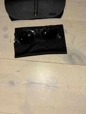 Svarta runda solglasögon från Black - Snygga svarta solglasögon från Black med rund form och mörka glas. Kommer med tillhörande fodral och putsduk. Perfekta för att ge din stil en cool touch.