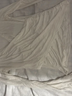 Vit långärmad topp - Säljer en enkel och stilren vit långärmad tröja tunt, mjukt material. Perfekt att slänga över en topp för en avslappnad look. Öppen framtill och utan knappar eller dragkedja. Passar till det mesta och är lätt att matcha.