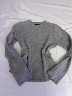 Grå stickad tröja från SHEIN - En enkel och stilren grå stickad tröja från SHEIN. Tröjan har rund halsringning, långa ärmar och är ribbstickad för en mjuk och bekväm känsla. Perfekt att matcha med jeans eller kjol för en avslappnad look.