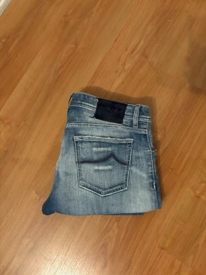 Jacob cohen - Säljer ett par snygga jacob cohen jeans med snygg tvätt med slitningar vid knät. Modellen har normal passform och raka ben, med fem fickor och bälteshällor. Perfekta för dig som gillar en tidlös och avslappnad stil.