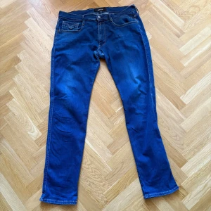 Blå Replay jeans straight fit - Snygga blå jeans från Replay med klassisk femficksdesign och raka ben. Jeansen har kontrastsömmar, läderpatch bak i midjan och broderad detalj på bakfickan. Perfekt för dig som gillar stilrena och tidlösa jeans med skön passform.