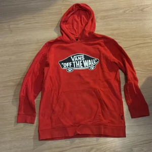 Röd Vans hoodie med tryck XL - Säljer en röd hoodie från Vans i storlek XL med stort 'Off The Wall'-tryck på bröstet. Tröjan har huva, magficka och långa ärmar. Materialet är mjukt och känns som bomull, perfekt för chill dagar. Skön passform och klassisk streetstil. Vet inte vad den här AI säger men säljer en röd Vans tröja som inte passar mig längre hör av er vid frågor. Är flexibel med pris 