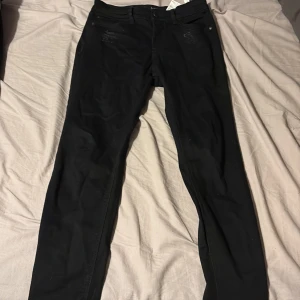 Svarta low waist jeans Stradivarius - Svarta jeans från Stradivarius i low waist-modell. Byxorna har skinny fit, klassiska fem fickor och diskreta slitningar framtill. Snygg och enkel design som passar till det mesta. Materialet är stretchigt och bekvämt.