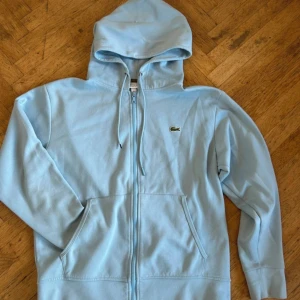 Ljusblå Lacoste hoodie - Stilren ljusblå lacoste hoodie utan besvär. Skriv om du har frågor
