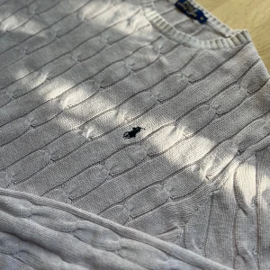 Ralph Lauren Kabelstickad Tröja Beige - Klassisk kabelstickad tröja från Ralph Lauren i beigefärgton.  Tröjan är nästan som ny ‼️ Har fått en svag rosa nyans efter tvätt, med det syns mest i visst ljus Försökte visa rosa nyansen i sista bild Men i övrigt mycket fint skick ‼️ Mjuk och bekväm perfekt för en preppy och tidlös look  Mått: Längd - 69 Axelbredd - 50cm