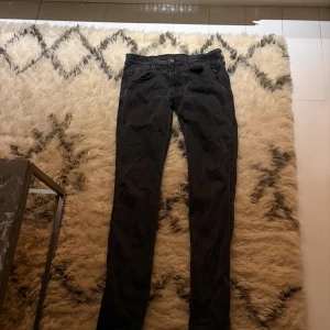 Svarta Replay jeans, waist 33/length 34 - Säljer ett par svarta jeans från Replay med klassisk femficksdesign och snygga detaljer på bakfickan. Modellen har normal passform och raka ben, tillverkade i mjukt jeanstyg. Perfekt för dig som gillar stilrena och tidlösa jeans.
