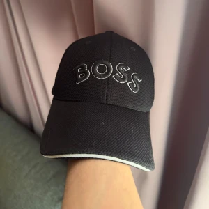 Boss keps - Boss Svart keps med vit kant och broderad "BOSS" logotyp framtill.