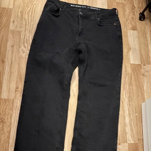 Svarta wide jeans midwaist - Svarta jeans med midwaist och wide passform. Klassisk femficksmodell med knapp och dragkedja. Midja 36 och längd 32, perfekt för dig som gillar en avslappnad och trendig look.