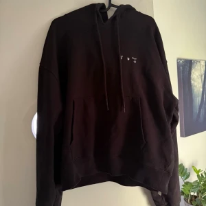 Svart Off-White hoodie med konstmotiv - Säljer en svart hoodie från Off-White med konstnärligt tryck på ryggen och liten logga framtill. Tröjan har huva med snörning och en stor magficka. Perfekt för dig som gillar streetwear och vill sticka ut med en unik design. Kommer inte ihåg exakt men köpt för 4000-6000. Prisförslag uppskattas!