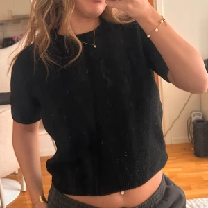 Svart stickad kortärmad tröja - En svart stickad tröja med korta ärmar och rund hals. Modellen är något croppad 