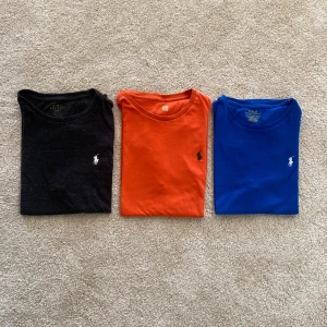 3-pack t-shirts från Polo Ralph Lauren - Säljer tre klassiska t-shirts från Polo Ralph Lauren i svart, orange och blå.  Alla har rund halsringning, kort ärm och den ikoniska broderade loggan på bröstet. Tillverkade i mjuk bomull för skön passform.      Storlekar: Svart M, Orange M, Blå S men passar M. OBS! Man behöver inte köpa alla tröjor utan man kan köpa någon separat men kontakta mig först i så fall.