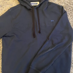 Marinblå hoodie från Jacob Cohën - Säljer en stilren marinblå hoodie från Jacob Cohën med broderad logga på bröstet. Tröjan är i  väldigt bra skick och är i extremt lyxigt material.