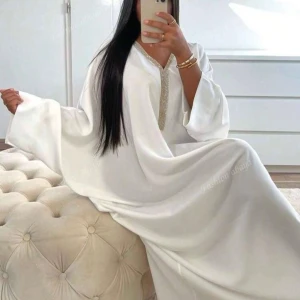 Vit butterfly abaya, helt ny! - Säljer en vit långklänning från Fashion Abaya med glittrig dekor vid halsringningen. Klänningen har vida ärmar och ett flowy, loose fit som ger en elegant look. Perfekt för dig som gillar stilrena och lyxiga vibes.