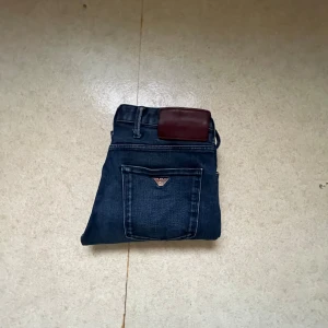 Emporio Armani mörkblå skinny jeans - Snygga mörkblå jeans från Emporio Armani med klassisk femficksdesign och logga på bakfickan. Jeansen har en slim och skinny passform, midwaist och är tillverkade i mjukt jeansmaterial med lätt stretch. Perfekta för dig som gillar stilrena och moderna jeans.