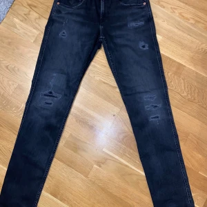 Replay Anbass jeans - strl:30/32. Köpta 08/10/2025, nypris 1421kr. använda  2ggr                                                                       Svarta Replay Anbass jeans med slim fit och snygga slitningar på benen. Klassisk femficksmodell med dragkedja och knapp, samt Replay-logga på bakfickan. Jeansen har en mörk tvätt och är tillverkade i stretchigt bomullsmaterial för skön passform.