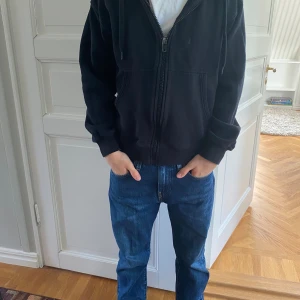 Svart hoodiejacka från Vaillent XS - Originalpris 399 kr. Svart hoodiejacka från Vaillent i storlek XS. Jackan har dragkedja framtill, huva med snörning och två fickor. Inga bemärkningar på defekter. Perfekt för en chill och avslappnad stil. 