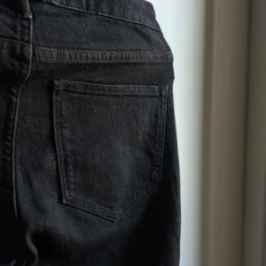 Svarta skinny jeans med smal passform - Snygga svarta jeans med klassisk femficksdesign och raka ben. Jeansen har normal midja, silverfärgad knapp och bälteshällor. Materialet är jeans med en mjuk känsla och de passar perfekt till en chill och stilren look.