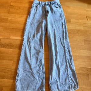 Wide leg jeans från Bershka - Snygga grå jeans från Bershka med wide leg-passform och klassisk femficksdesign. Byxorna har hög midja, dragkedja och knapp framtill samt raka, vida ben som ger en chill och trendig look. Perfekta för dig som gillar loose fit och streetstyle.