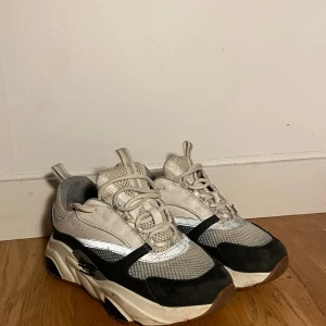 Chunky sneakers i svart och vitt - Säljer ett par chunky sneakers med plattformssula i svart, vitt och grått. Ovandelen har mesh och skinnpaneler, samt snörning och rund tå. Snyggt sportig vibe och riktigt feta detaljer på sulan. Perfekt för dig som gillar statement-skor.