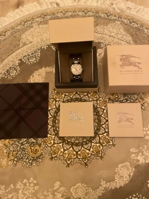 Burberry klocka - unisex  - Säljer min stilrena Burberry-klocka, modell BU9000, köpt 2018 för 545 € (ca 6 000 kr). Den är knappt använd och har mest legat i sin låda sedan dess. Klockan är i mycket fint skick, endast några pyttesmå repor på armbandet, som bara syns om man tittar nära.  Specifikationer: 	•	Modell: BU9000 	•	Swiss Made 	•	Safirglas (Sapphire Crystal) 	•	Rostfri stållänk 	•	Vattentålig: 50M / 165 feet  Skick:  Mycket gott begagnat skick. Fullt fungerande. Minimalt slitage.  Detta följer med: 	•	Original Burbe