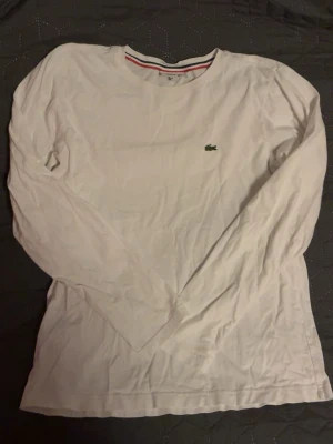 Vit lacoste - Vit långärmad lacoste tröja i st 14 years, men på mig som tjej så sitter den som S fast lite kortare men inte mycket. Köpt för några år sen men fortfarande i mycket bra skick 