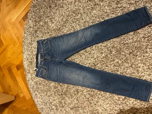 Replay jeans - Feta Replay jeans i en blå fade. Skicket på byxorna är bra, har någon slitning som förekommit på knät men tycker själv att den endast ser bra ut.  Storleken är 30/32