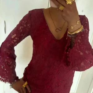 Vinröd spetsblus med v-ringning - Säljer en vinröd blus i spets med v-ringad hals och långa, lätt utsvängda ärmar. Blusen har ett romantiskt uttryck med genombrutet spetsmönster och figurnära passform. Perfekt för dig som vill sticka ut med en elegant look.