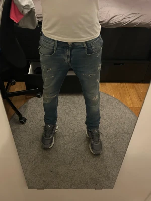 Replay jeans, blå, slim fit, storlek 29/32 - Säljer ett par snygga Replay jeans i blå tvätt med slitna detaljer och distressed look. Modellen är slim fit med normal midja och raka ben. Tillverkade i ekologisk bomull för extra komfort. Perfekt för dig som gillar streetstyle och vill ha en cool vibe. Modell 180 ca