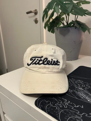 Titleist keps i vit  - Vit Titleist keps med loggor på sidorna där det står pro v1 och FJ (footjoy). No size för har ett justerbart spänne där bak som passar alla.