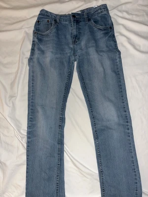 Ljusblå raka jeans - Snygga ljusblå jeans med klassisk femficksdesign och raka ben. Jeansen har normal passform och är tillverkade i mjukt denimtyg som ger en skön känsla. Perfekta för dig som gillar en enkel och stilren look.