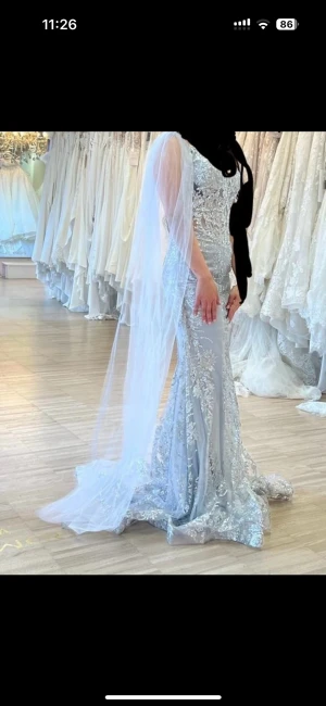 Glittrig silver långklänning med släp - Säljer en magisk långklänning i silver med glittriga paljetter och broderier. Klänningen har v-ringning, smala axelband och ett långt släp i tunn tyll som ger extra wow-känsla. Perfekt för dig som vill sticka ut och glänsa på bal eller fest.