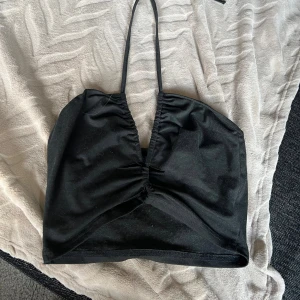 Svart topp  - Säljer en svart  topp från SHEIN i storlek M. Toppen har smala band som knyts i nacken, toppen har en v-ringning  vid brösten och är i mjukt och stretchigt material .