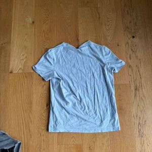 Ljusblå basic t-shirt i bomull /Morris - En enkel ljusblå t-shirt med korta ärmar och rak passform. Tillverkad i mjuk bomull, perfekt för en clean och avslappnad stil. Liten diskret logga nertill på framsidan. Klassisk rund halsringning.