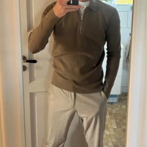 Brun stickad half zip-tröja Samsøe - Snygg brun stickad tröja från Samsøe Samsøe med krage och half zip-dragkedja. Perfekt för lager-på-lager och funkar året runt. Långärmad och i mjukt material som känns skönt mot huden. Enkel att matcha med både jeans och chinos.