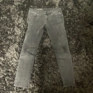 Replay grå jeans, waist 29 - Säljer ett par grå jeans från Replay i storlek 29. Byxorna har smal passform, raka ben och klassisk femficksdesign. Snygga sömdetaljer över knäna och diskret Replay-logga vid fickan. Perfekta för dig som gillar stilrena och moderna jeans.