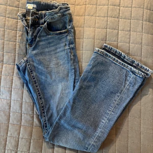 Blå bootcut jeans från Gina Tricot 164 - Stl 164 - Snygga blå jeans från Gina Tricot i modell med bootcut. Klassisk femficksdesign, normal passform och medelblå tvätt. Jeansen har dragkedja och knapp framtill samt bälteshällor. Perfekta för dig som gillar en avslappnad och trendig look.