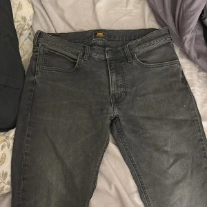 Svarta Lee Luke jeans W32 L32 - Säljer ett par svarta Lee Luke jeans i storlek W32 L32. Jeansen har en klassisk femficksdesign, raka ben och snygg tvättad finish. Tillverkade i bomull med en bekväm passform och diskreta Lee-detaljer på bakfickan.