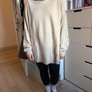 Oversized beige polotröja i kashmir - Supermjuk och oversized beige polotröja i 100% kashmir. Långärmad modell med bred, stor polokrage och ribbade muddar. 