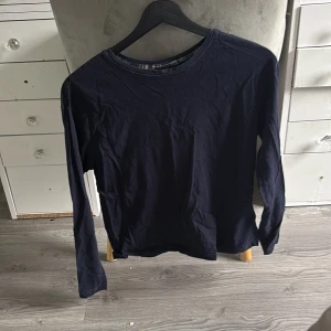 Mörkblå långärmad tröja - En basic mörkblå långärmad tröja i mjuk bomull. Perfekt att ha som lager eller bara som den är. Enkel och stilren design med rund halsringning och normal passform.