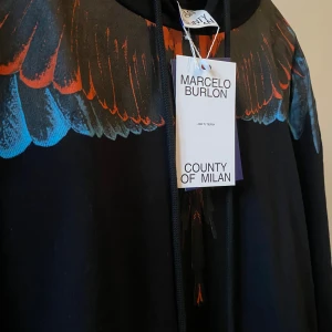 Marcelo Burlon Hoodie - Säljer nu denna Marcelo burlon hoodie helt nu med prislapp och har inte kommit till användning än är i storlek M och sitter som den ska. Kom gärna fram med bud och så gör vi en snabb affär.