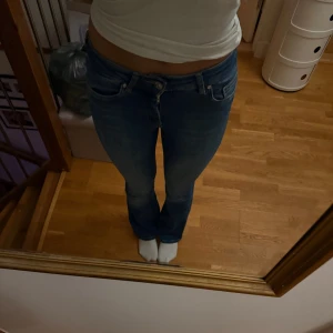 Blå bootcut jeans - Säljer ett par blå jeans med bootcut-modell. Jeansen har klassisk design och är tillverkade i ett stretchigt jeansmaterial som sitter snyggt på kroppen. Perfekta för dig som gillar en tidlös och avslappnad stil. Säljer då jag ej använder de längre och inte gillar helt hur de sitter på mig. Priset kan diskuteras.