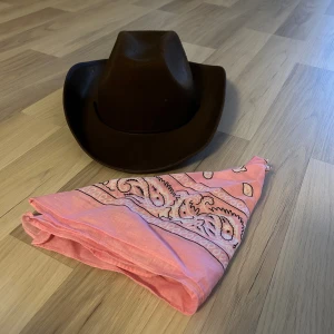 Brun cowboyhatt och rosa bandana - Säljer en klassisk brun cowboyhatt och en rosa bandana. Perfekt för halloween eller temafest!