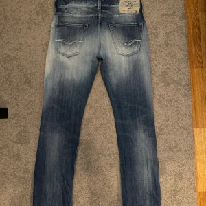 Replay jeans blå, storlek 30/32 - Säljer ett par Replay jeans med slitna detaljer och galet snygg tvätt. Klassisk raka ben och normal passform.