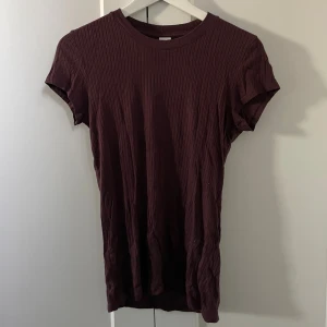 Vinröd ribbad t-shirt från Twist & Tango - Säljer en vinröd t-shirt från Twist & Tango med ribbad struktur och rund hals. T-shirten har korta ärmar och är gjord i mjuk bomull som sitter skönt mot kroppen, funkar när de är lite kallare ute!