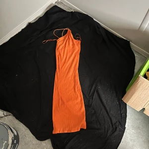 Orange ribbad långklänning från Zara - Säljer en snygg orange långklänning från Zara med smala axelband och ribbad struktur. Klänningen har en figurnära passform och är ärmlös, perfekt för varma dagar eller när du vill sticka ut med färg.