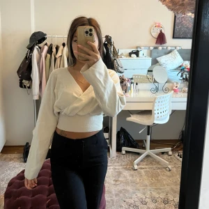 Beige omlottopp från Bikbok - Säljer en beige croppad omlottopp från Bikbok med lång ärm och v-ringning. Toppen har en ribbad midja och är i mjukt, stretchigt material som sitter snyggt på kroppen.