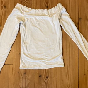 Vit offshoulder topp från BikBok - Säljer en stilren vit offshoulder topp från BikBok i storlek XS. Toppen har långa ärmar och en snygg, axelbar design som ger en trendig look. Perfekt att matcha med jeans eller kjol för en fräsch outfit.