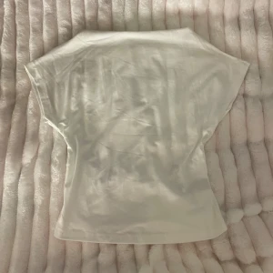 Vit top med öppen rygg - Säljer en vit topp med korta ärmar och snygg öppen rygg.